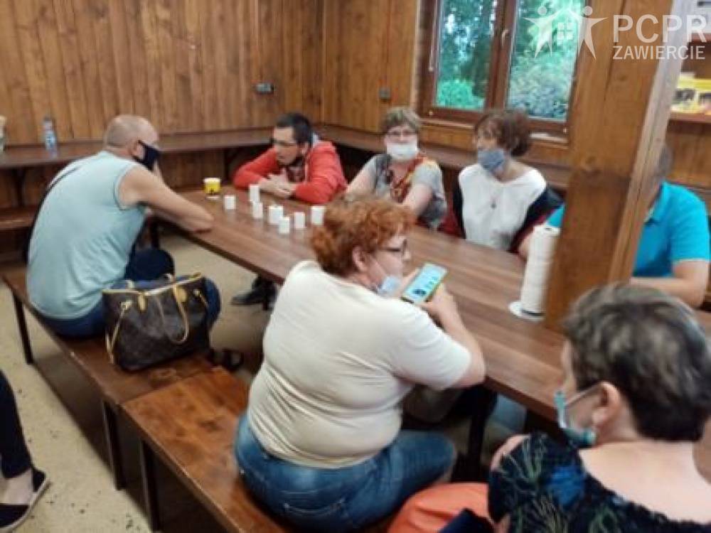 Zdjęcie: Grupa mężczyzn i kobiet siedząc przy stole ogląda produkty pszczelarskie